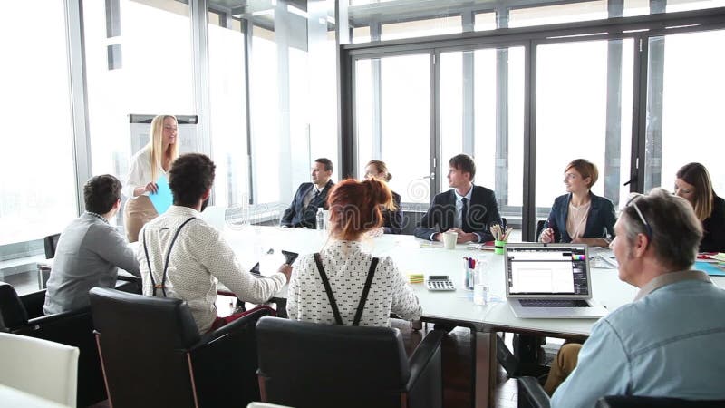 Bedrijfsmensen die bij lijst zitten terwijl vrouwelijke collega die presentatie geven