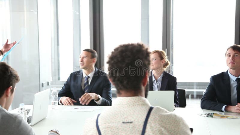 Bedrijfsmensen die bij lijst zitten terwijl vrouwelijke collega die presentatie geven