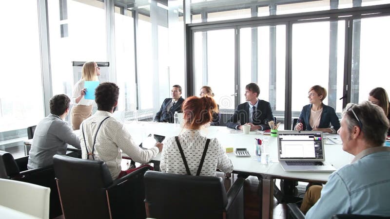 Bedrijfsmensen die bij lijst zitten terwijl vrouwelijke collega die presentatie geven