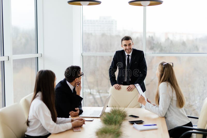 Business meeting. Business people in formalwear discussing with leader something while sitting together at the table. Business meeting. Business people in formalwear discussing with leader something while sitting together at the table