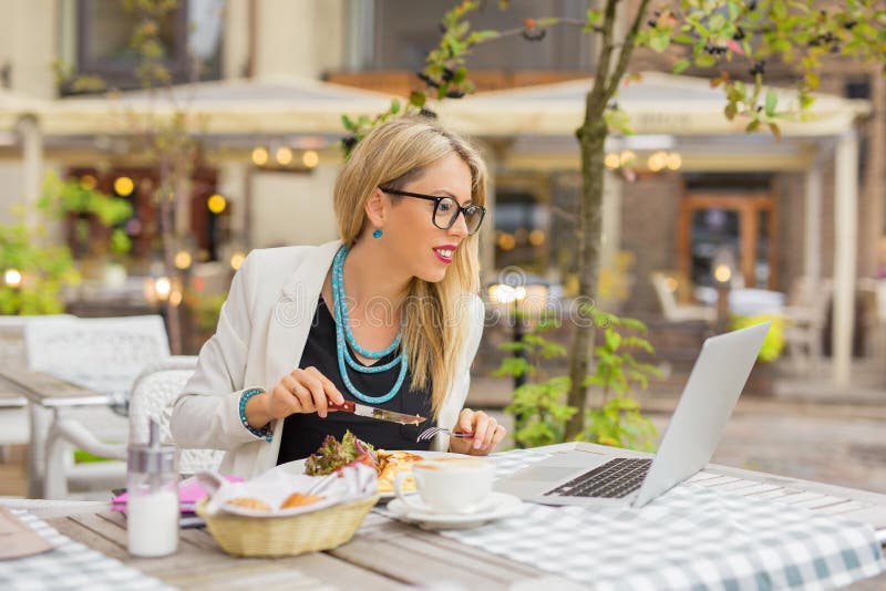 Bedrijfsvrouw die lunch eten en aan laptop werken royalty-vrije stock foto Bedrijfsvrouw die lunch eten en aan laptop werken royalty-vrije stock foto