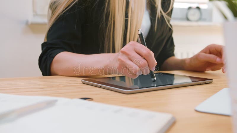 Bedrijfsvrouwen die aan tablet in bureau werken Aantrekkelijk blond wijfje met lang haar in elegante kostuumzitting bij houten