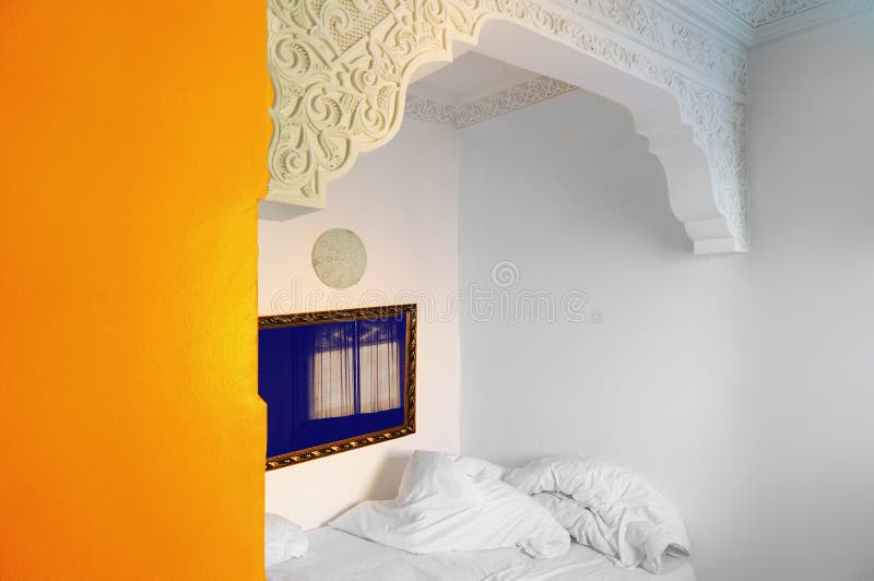 Bedroom with white and orange walls, a mirror with window refle