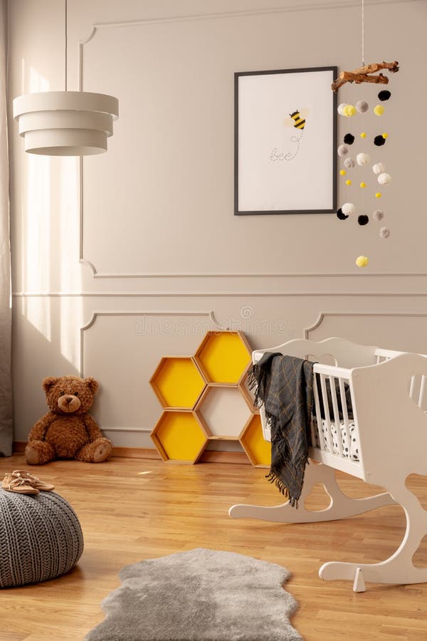 Bee poster, honeycombs, teddy bear on the floor and crib in a toddler room interior. Real photo royalty free stock images Bee poster, honeycombs, teddy bear on the floor and crib in a toddler room interior. Real photo royalty free stock images