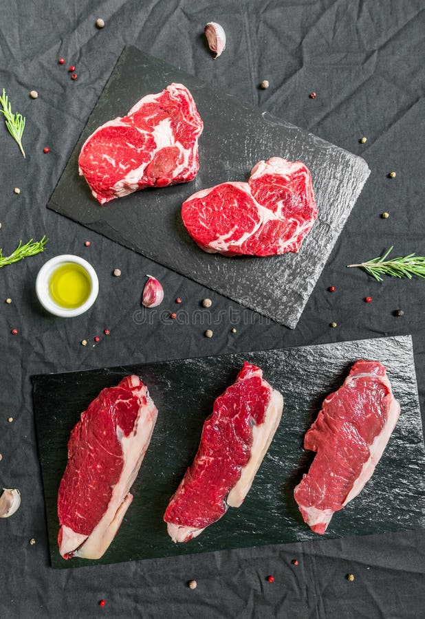 Beef Cow Meat Steaks with Spices and Herbs Against Black Background