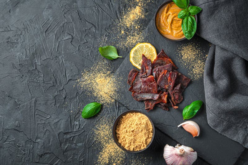 Beef Jerky with Mustard, Garlic and Basil on a Black Background. Stock