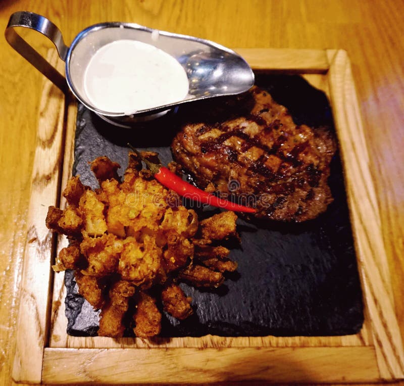 Beef Knuckle Cooked on the Grill. Presented on a Hot Stone, with Baked Onions and Sauce Stock