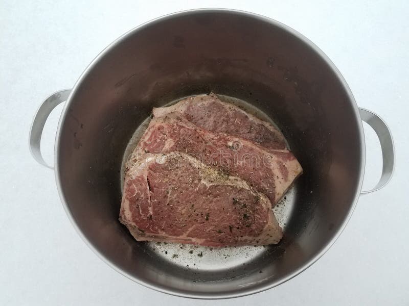 Beef Steak with Seasoning and Liquid in Metal Pot on Snow Stock Photo
