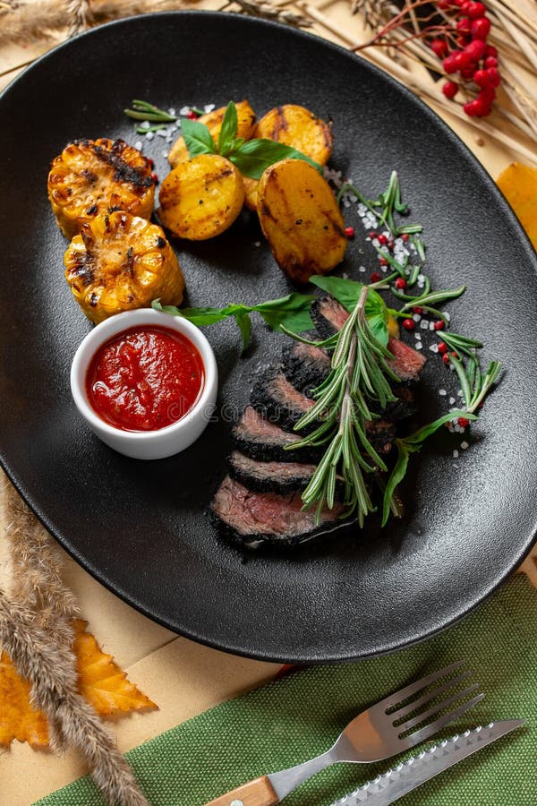 Beef Steak with a Side Dish of Grilled Corn Decorated with Rosemary on