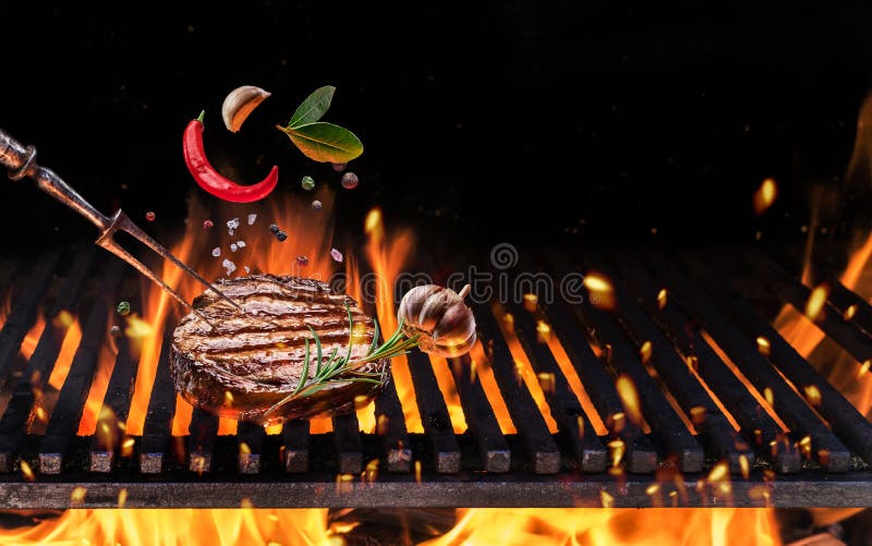 Beefsteak with spices fly over the flaming grill barbecue fire stock image Beefsteak with spices fly over the flaming grill barbecue fire stock image