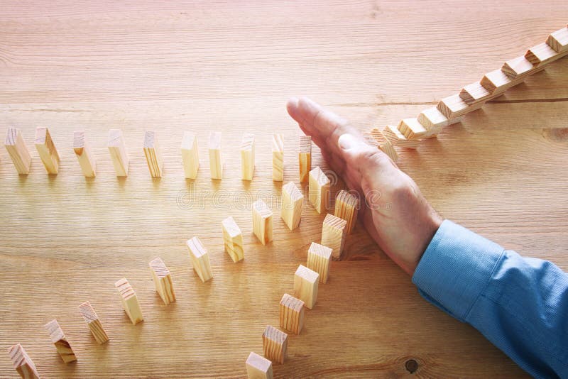 Image of male hand stopping the domino effect. retro style image executive and risk control concept. Image of male hand stopping the domino effect. retro style image executive and risk control concept