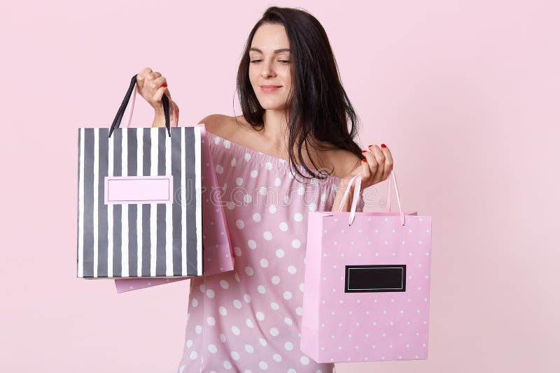 Beeld van het verbazen van jonge donkerbruine vrouw die stipkleding dragen, die met het winkelen zakken stellen en het kijken nee stock fotografie Beeld van het verbazen van jonge donkerbruine vrouw die stipkleding dragen, die met het winkelen zakken stellen en het kijken nee stock fotografie
