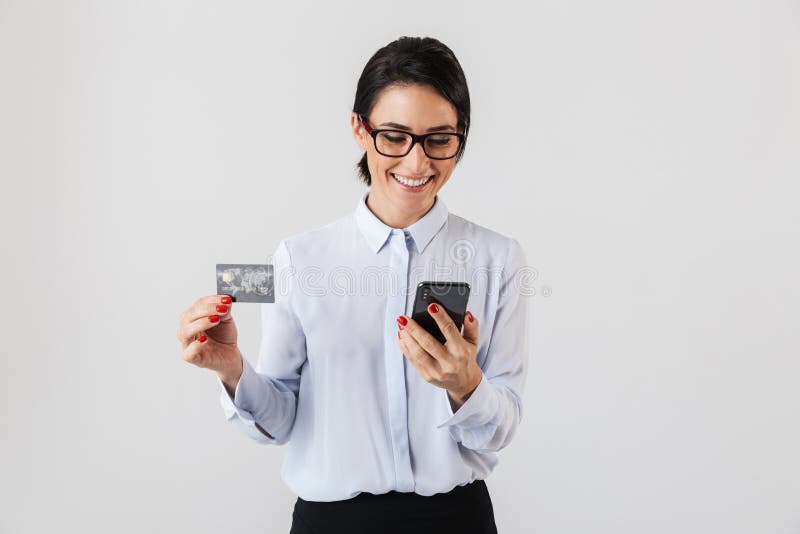 Beeld van jonge bureauvrouw die oogglazen dragen die mobiele die telefoon en creditcard houden, over witte achtergrond wordt geïs stock afbeeldingen Beeld van jonge bureauvrouw die oogglazen dragen die mobiele die telefoon en creditcard houden, over witte achtergrond wordt geïs stock afbeeldingen