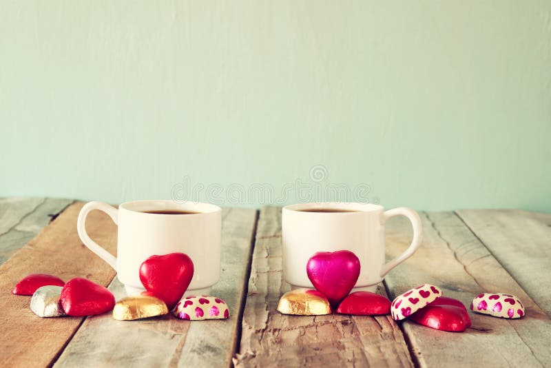 Beeld van twee rode chocolade van de hartvorm en paarkoppen van koffie op houten lijst Het concept van de de Dagviering van Valen stock foto's Beeld van twee rode chocolade van de hartvorm en paarkoppen van koffie op houten lijst Het concept van de de Dagviering van Valen stock foto's
