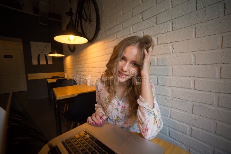 Beeld van vrij jong krullend hagelmeisje met laptop die en in een koffie glimlachen zitten stock foto's Beeld van vrij jong krullend hagelmeisje met laptop die en in een koffie glimlachen zitten stock foto's