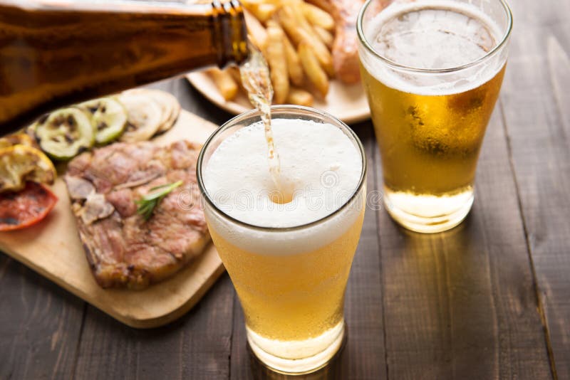 Beer being poured into glass with gourmet steak and french fries stock image Beer being poured into glass with gourmet steak and french fries stock image