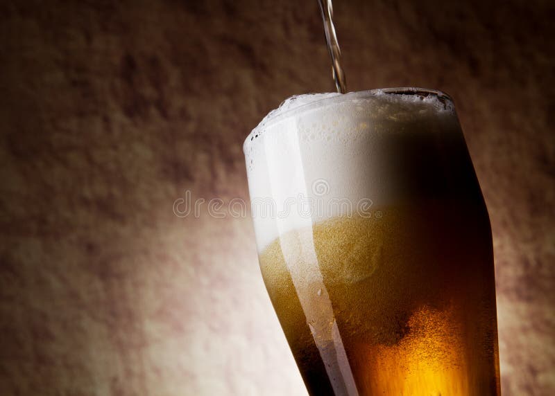 Beer into glass on a old stone background