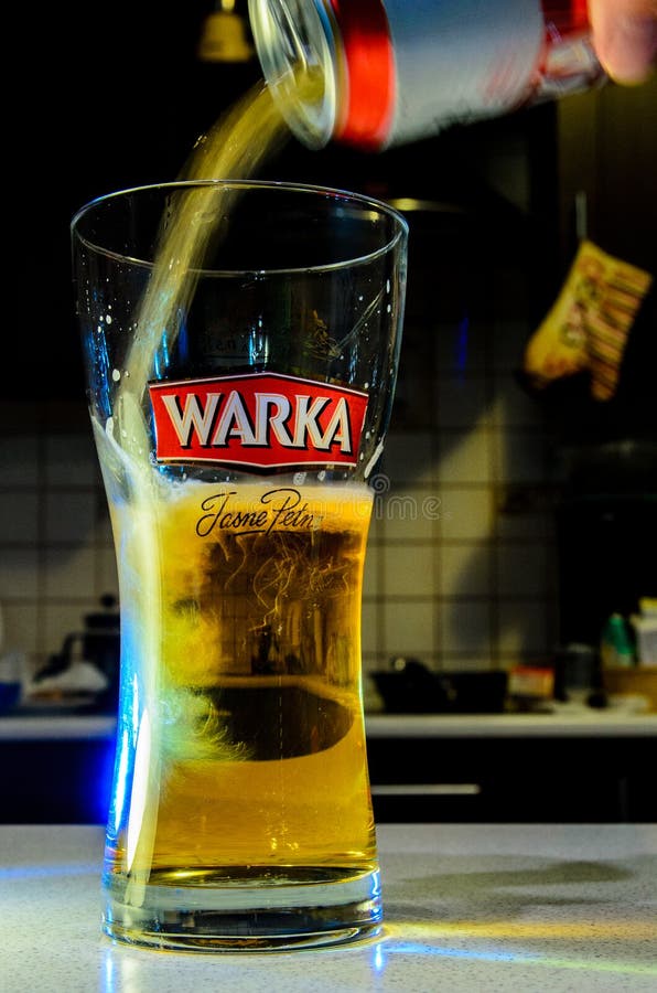 Beer Pouring from Can into Glass on Blurred Kitchen Editorial Image