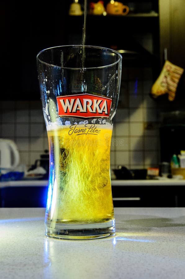 Beer Pouring into Glass on Blurred Kitchen Editorial Stock Image
