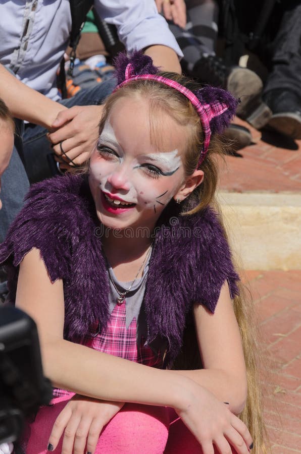 Beer-Sheva, ISRAEL - March 5, 2015: Girl with make-up cat with purple ears and cape, sits