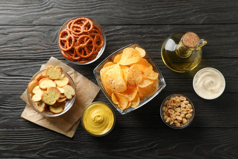 Beer snacks, potato chips, beer nuts, sauces, olive oil on wooden background, space for text royalty free stock photos Beer snacks, potato chips, beer nuts, sauces, olive oil on wooden background, space for text royalty free stock photos