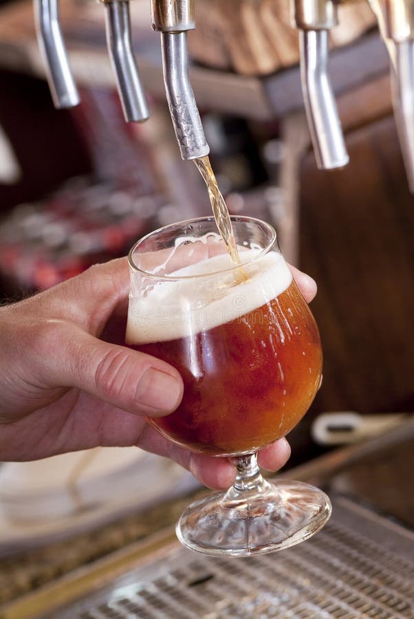 Brewer fills a glass with beer on tap