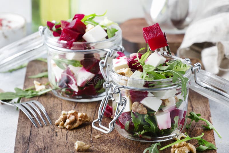 Beet salad with arugula, goat cheese and nuts, trendy salad jar, gray kitchen table background, selective focus
