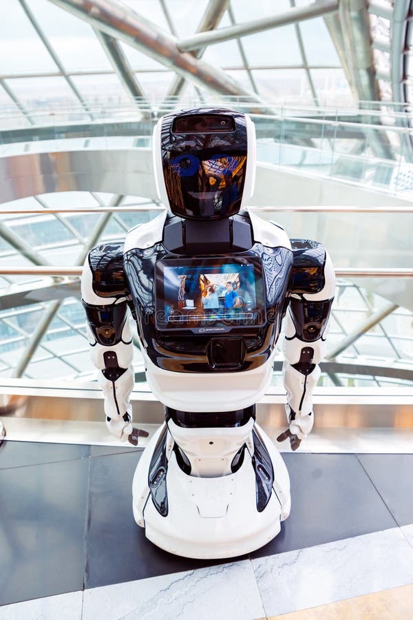 Befordra robofoto i full längd med bild av personer som visas i modern teknisk inredning. robotens leende ansikte. royaltyfria foton
