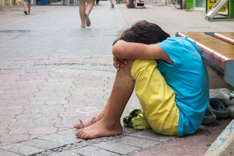Beggar child boy. KOMOTINI, GREECE - JULY 5: Abused and unclean beggar child boy on the sidewalk on July 5, 2014 in Komotini, Greece abused and unclean stock photography Beggar child boy. KOMOTINI, GREECE - JULY 5: Abused and unclean beggar child boy on the sidewalk on July 5, 2014 in Komotini, Greece abused and unclean stock photography