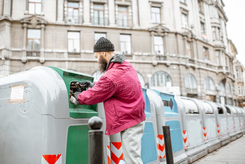 Beggar searching glass bottles in the trash. Homeless beggar searching glass bottles to surrender in the trash container at the city stock image Beggar searching glass bottles in the trash. Homeless beggar searching glass bottles to surrender in the trash container at the city stock image