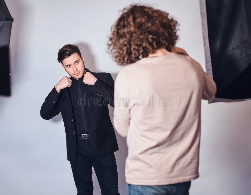 Beginnerfotograaf bij een fotospruit in een studio met een elegant geklede kerel royalty-vrije stock foto Beginnerfotograaf bij een fotospruit in een studio met een elegant geklede kerel royalty-vrije stock foto