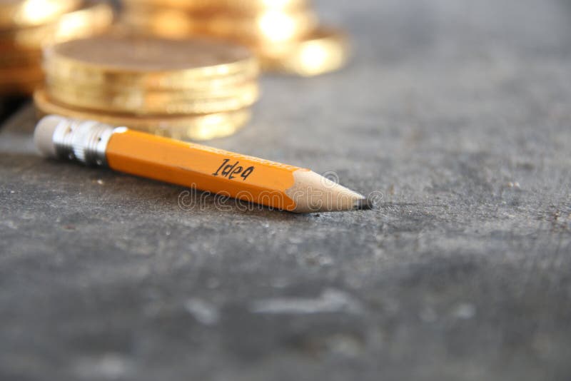 Begrepp - affärsidé Blyertspenna med inskriften och guld- mynt royaltyfri bild Begrepp - affärsidé Blyertspenna med inskriften och guld- mynt royaltyfri bild