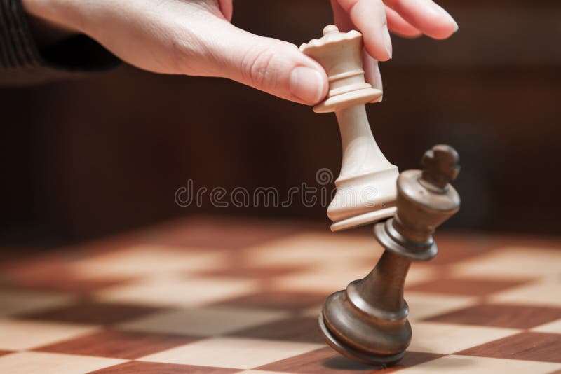 Begrepp: kvinnan som dominerar mannen En kvinnas hand ger schackmatt till konungen med drottningen p? en tr?schackbr?de, med arkivfoto Begrepp: kvinnan som dominerar mannen En kvinnas hand ger schackmatt till konungen med drottningen p? en tr?schackbr?de, med arkivfoto