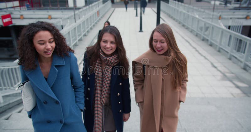 Begreppet 'flickmakt' och 'feminitet'. Tre unga leende vackra kvinnor från flera olika etniska företag går tillsammans på gatan arkivfilmer