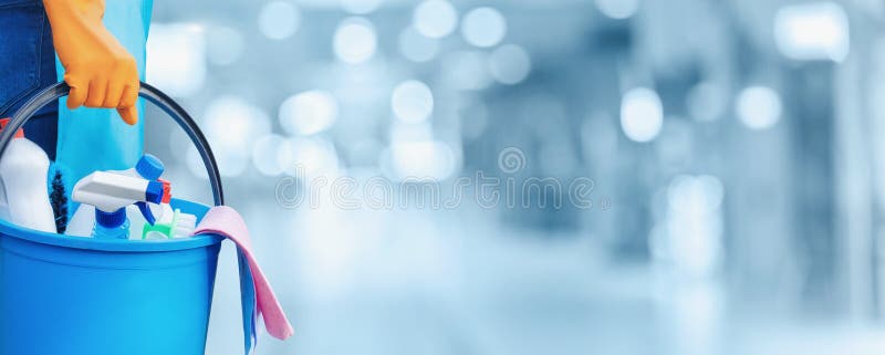 The concept of cleaning service. Cleaning lady hand holds a bucket of detergents on a blurred background. The concept of cleaning service. Cleaning lady hand holds a bucket of detergents on a blurred background