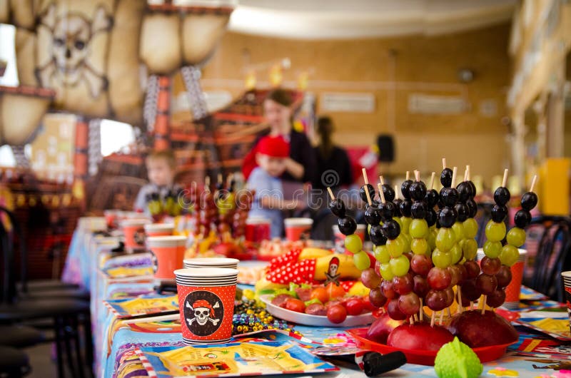 Behandelde feestelijke lijst in piraatsymboliek met voedsel op een piraatpartij stock foto Behandelde feestelijke lijst in piraatsymboliek met voedsel op een piraatpartij stock foto