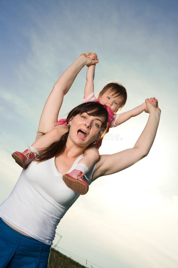 A view of a happy woman carrying a baby on her shoulders. A view of a happy woman carrying a baby on her shoulders.