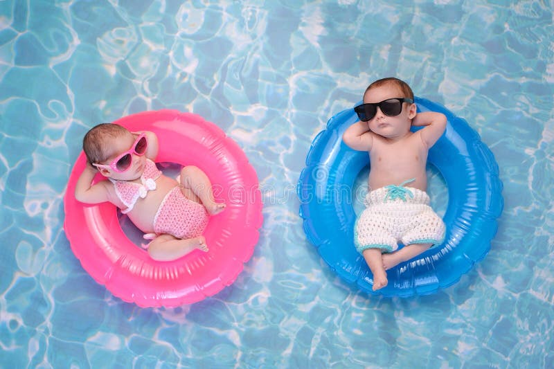 Two month old twin baby sister and brother sleeping on tiny, inflatable, pink and blue swim rings. They are wearing crocheted swimsuits and sunglasses. Two month old twin baby sister and brother sleeping on tiny, inflatable, pink and blue swim rings. They are wearing crocheted swimsuits and sunglasses.