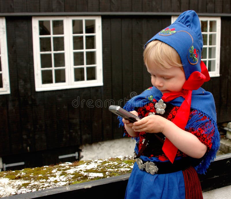 Baby girl (2 y.o.) in Faroese national costume using a mobile phone during St. Olaf's Days (the national holidays). Baby girl (2 y.o.) in Faroese national costume using a mobile phone during St. Olaf's Days (the national holidays).