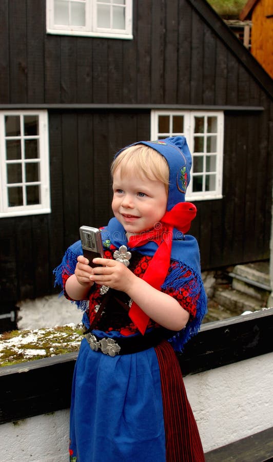 Baby girl (2 y.o.) in Faroese national costume using a mobile phone during St. Olaf's Days (the national holidays). Baby girl (2 y.o.) in Faroese national costume using a mobile phone during St. Olaf's Days (the national holidays).
