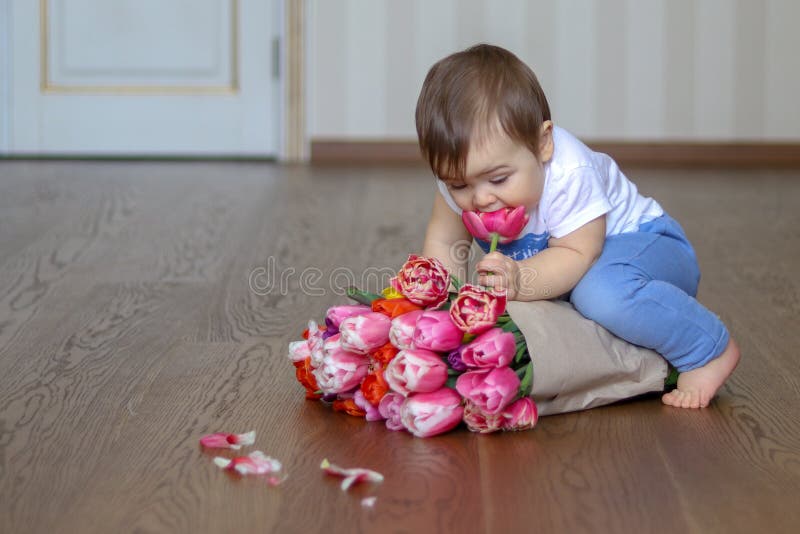 Behandla som ett barn lite pojkesammanträde på gruppen av rosa tulpan och att lukta en blomma arkivfoto Behandla som ett barn lite pojkesammanträde på gruppen av rosa tulpan och att lukta en blomma arkivfoto