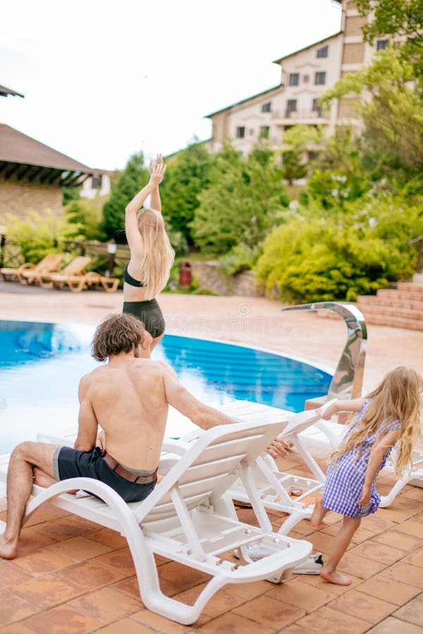 Behandla som ett barn och föräldrar som kopplar av på sunbed nära pöl på semesterorten Dana flickor, par, familj på semesterorten fotografering för bildbyråer Behandla som ett barn och föräldrar som kopplar av på sunbed nära pöl på semesterorten Dana flickor, par, familj på semesterorten fotografering för bildbyråer