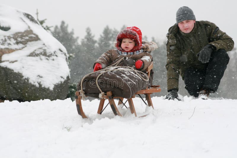 A little baby boy sledding with his father. First winter for baby. A little baby boy sledding with his father. First winter for baby.