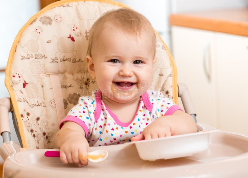 Smiling baby eating food on kitchen. Smiling baby eating food on kitchen