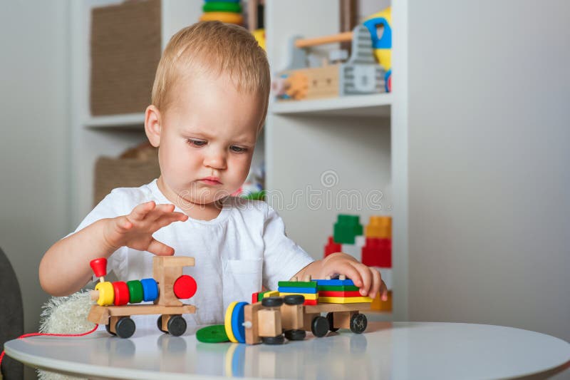 Bei bambini giocano con giocattoli in legno in asili d'infanzia o in locali chiusi per bambini e copiano spazio immagini stock libere da diritti
