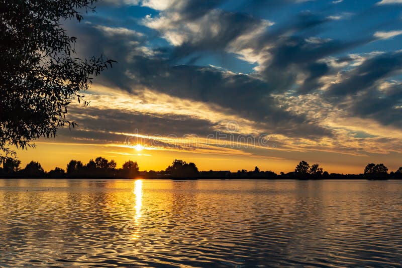 Bei cieli nuvolosi porpora durante il tramonto nei plas di Zoetermeerse del lago immagine stock libera da diritti Bei cieli nuvolosi porpora durante il tramonto nei plas di Zoetermeerse del lago immagine stock libera da diritti