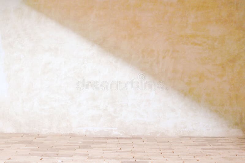 Beige cement wall in empty room with light and shadow stock image