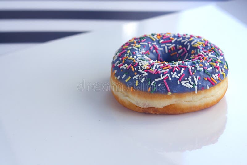 Beignet doux avec le glaçage et le saupoudrage de couleur, sur un fond blanc, vue de côté image libre de droits Beignet doux avec le glaçage et le saupoudrage de couleur, sur un fond blanc, vue de côté image libre de droits