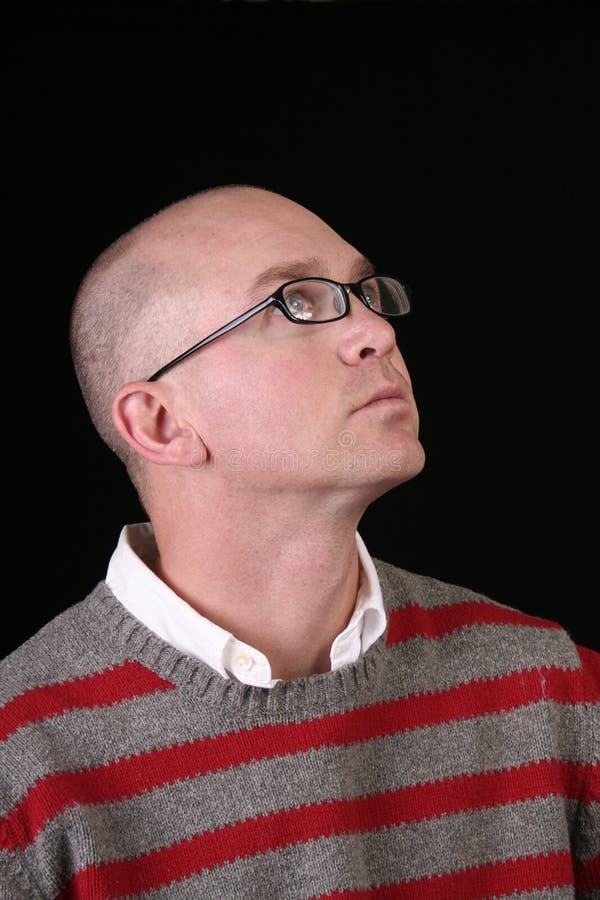 A bald man in a striped sweater looking up at something. A bald man in a striped sweater looking up at something.