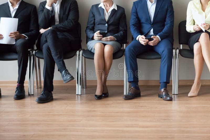 Beine von den verschiedenen Arbeitskandidaten, die der Reihe nach Interview warten lizenzfreies stockbild